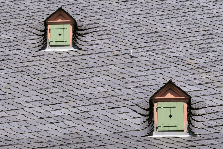 A slate rooftop with dormer windows